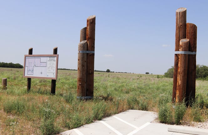 Wooden pillars and a concrete pad mark the entrance to the prairie park.
