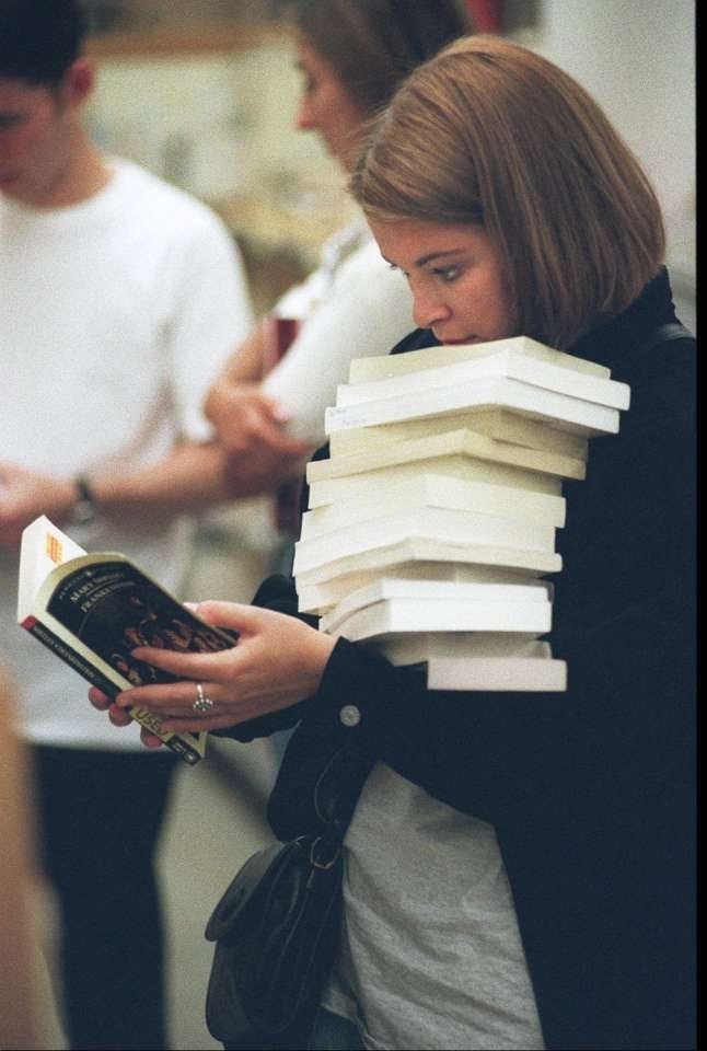 This may contain: a woman holding a stack of books in her hands