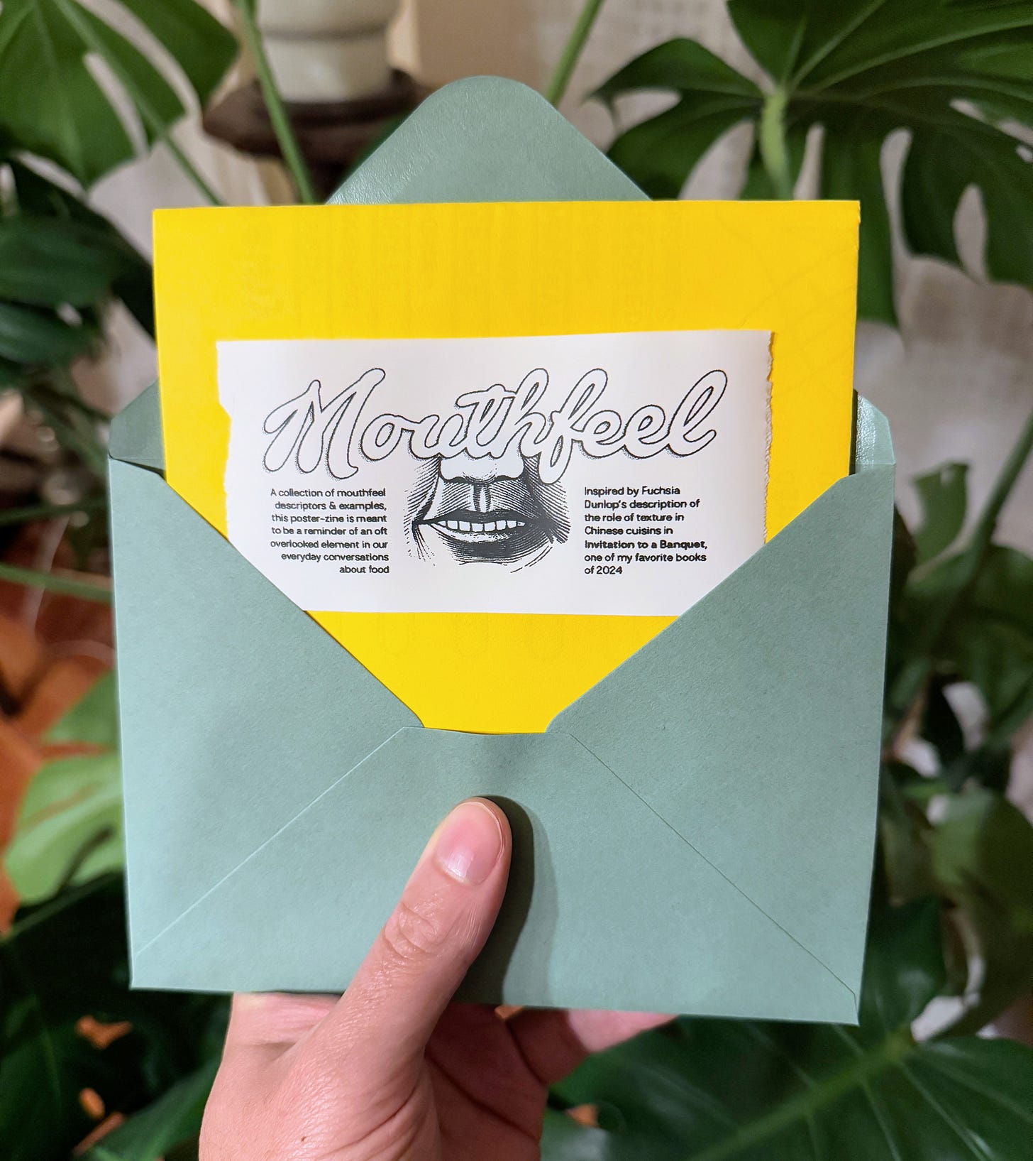 Hand holding mouthfeel zine in envelope