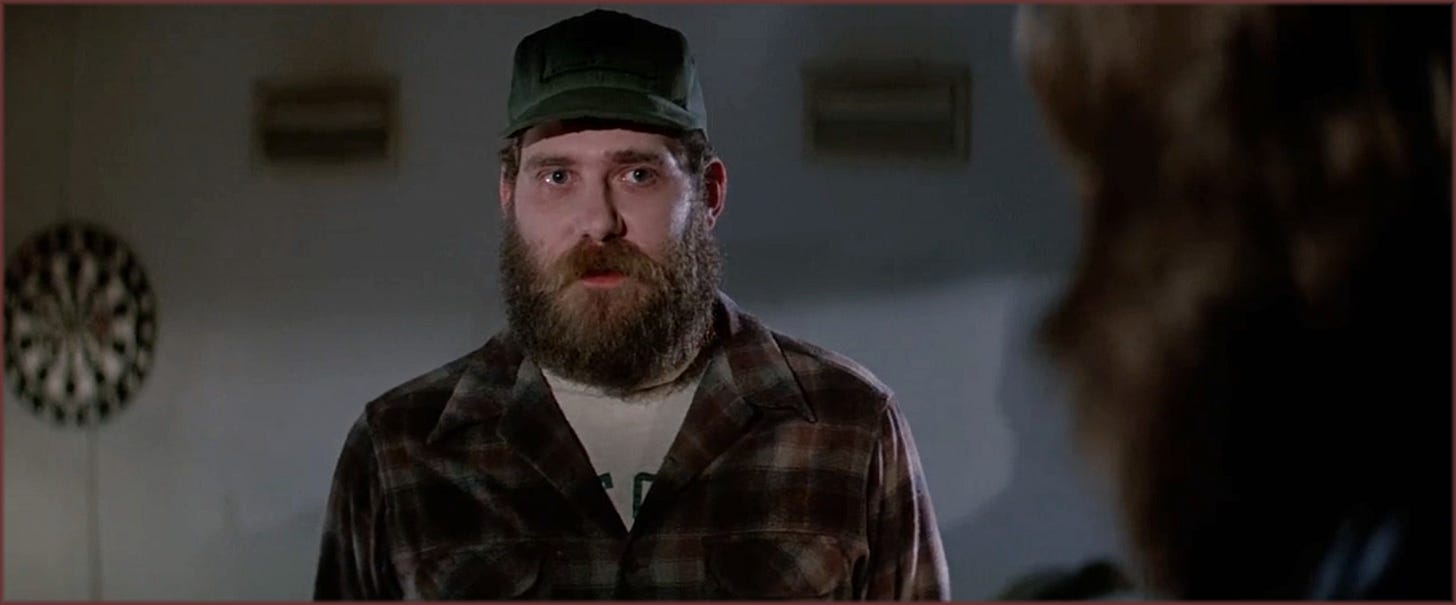 Close-up from The Thing (1982): Clark (Richard Masur) in the moments before MacReady shoots him during the blood test sequence, expression tense and unreadable.