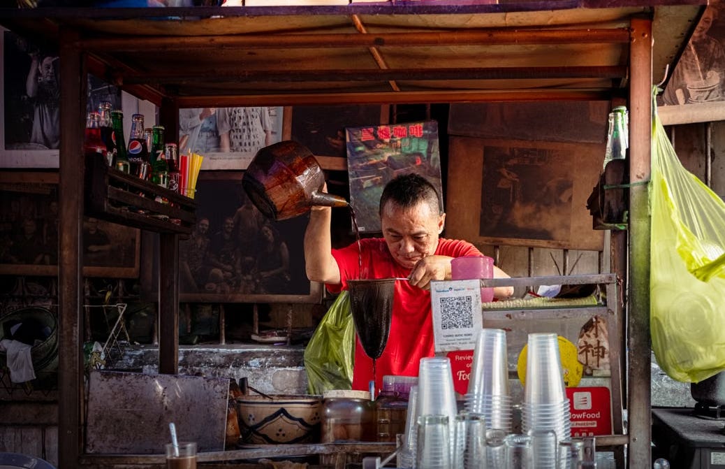 Street vendor prepares traditional coffee at a bustling stall in Ho Chi Minh City, capturing vibrant local coffee culture. Street vendor prepares traditional coffee at a bustling stall in Ho Chi Minh City, capturing vibrant local coffee culture.