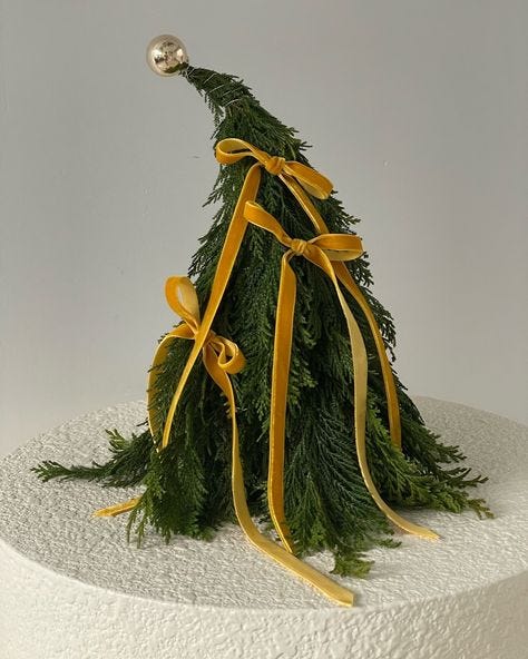 This may contain: a white cake topped with a green and yellow christmas tree decoration on top of it