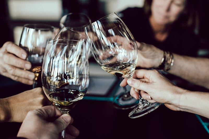 Four people clink wine glasses with each other. Four people clink wine glasses with each other.