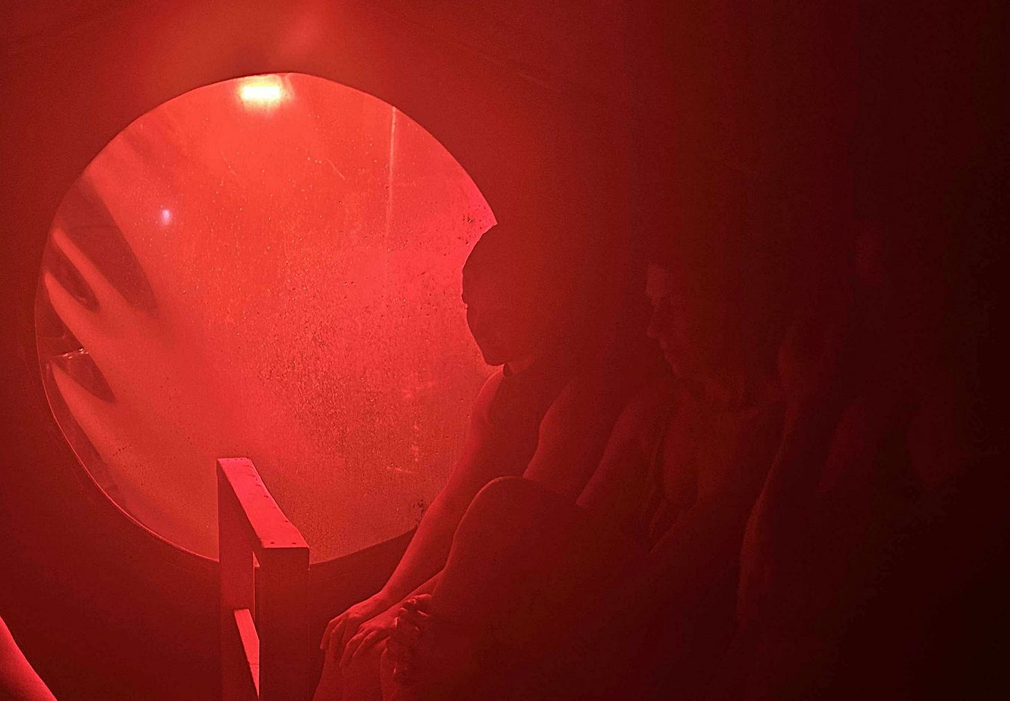 three women in a steamy sauna, red glow of fire