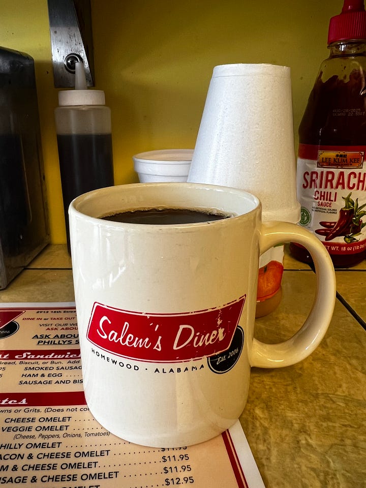 picture of a mug of coffee and a stainless steel milk pitcher on a yellow diner counter