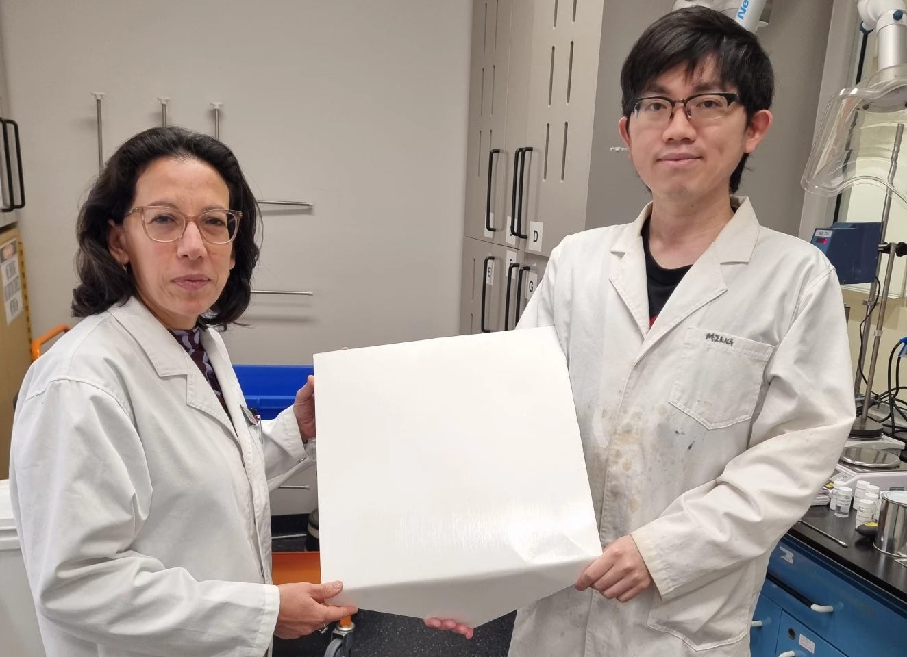 Professor Chiara Neto (left) and Dr Ming Chiu hold one of the experimental tiles with the paint-like substance in their labs at the University of Sydney