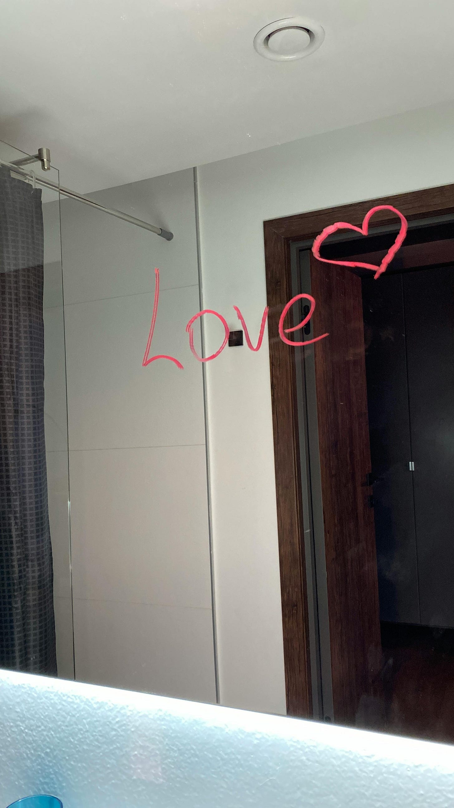 A photo of a bathroom mirror that says "love" with a heart in red lipstick A photo of a bathroom mirror that says "love" with a heart in red lipstick