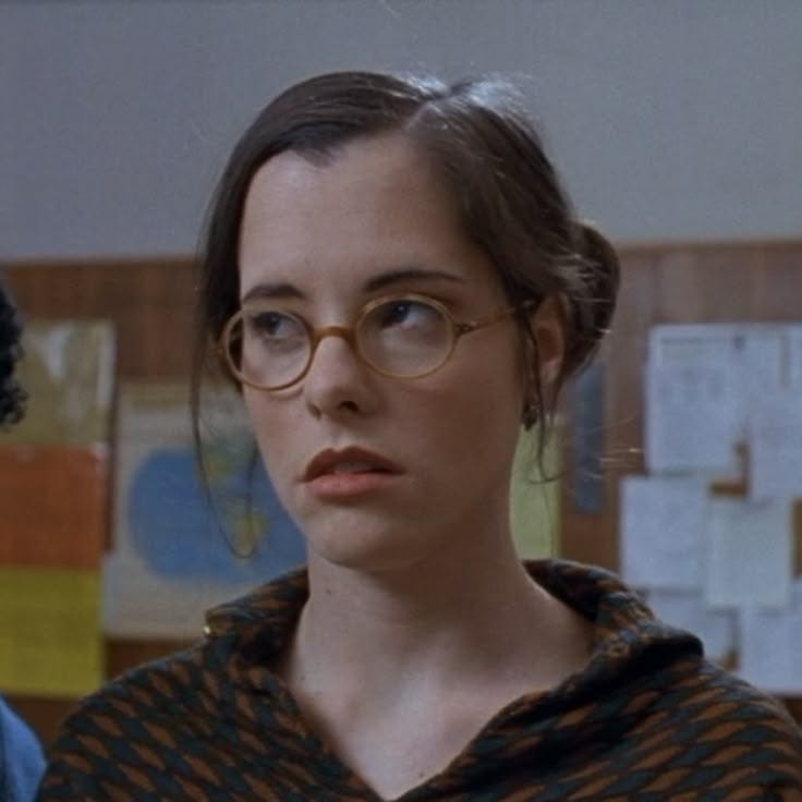 This may contain: a woman wearing glasses standing in an office