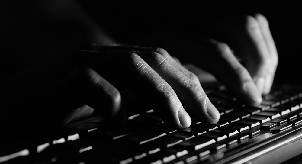 A writer's hands dance over the keyboard in the dark