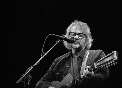 Black-and-white photos of each member of the Tweedy band performing live