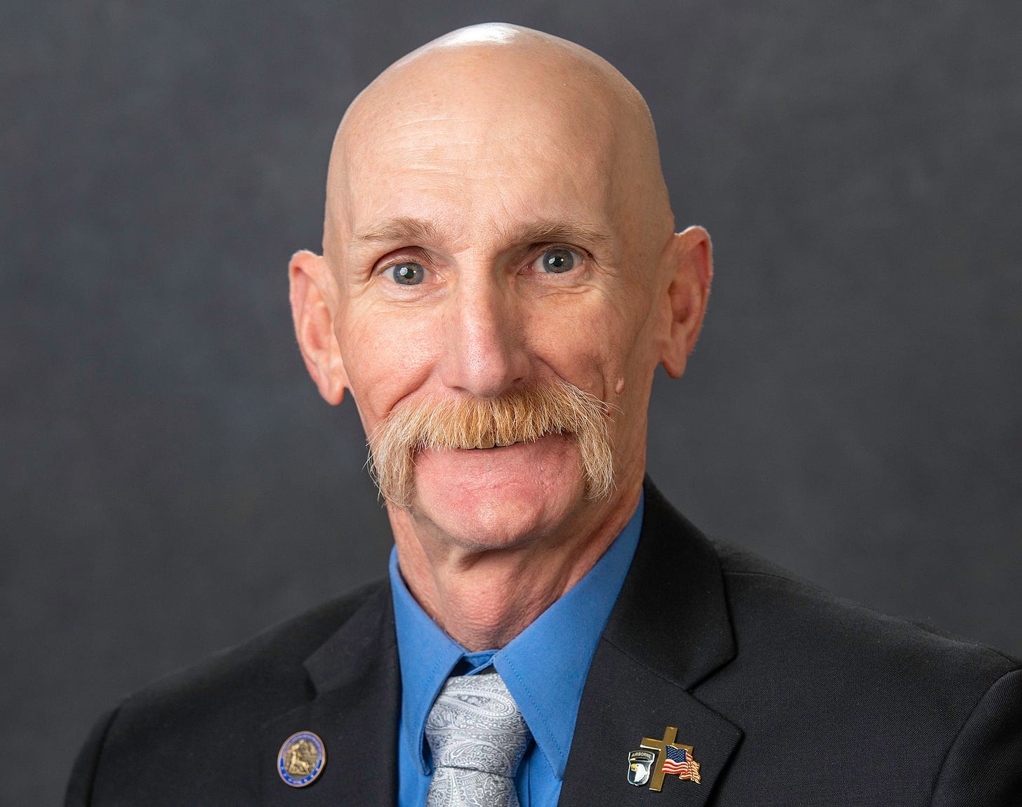 man with shaved head and mustache in suit