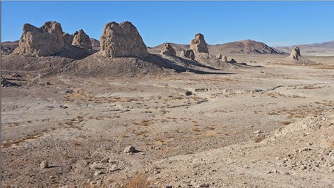 Barren desert landscape with cone‑shaped rock pinnacles scattered across the horizon under a clear blue sky.