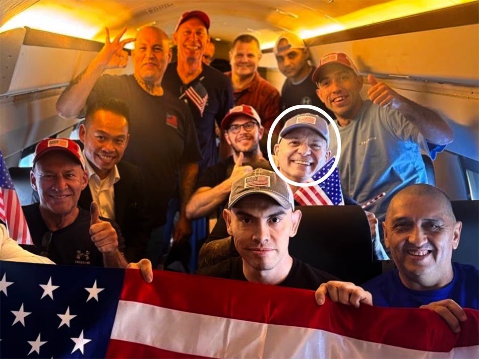 A group of men inside the cabin of a jet, all smiling and holding up American flags. One, whose face is circled, is a triple murderer. A group of men inside the cabin of a jet, all smiling and holding up American flags. One, whose face is circled, is a triple murderer.