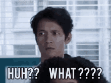 a man is standing in front of a window and making a funny face with the words huh ? what ? a man is standing in front of a window and making a funny face with the words huh ? what ?