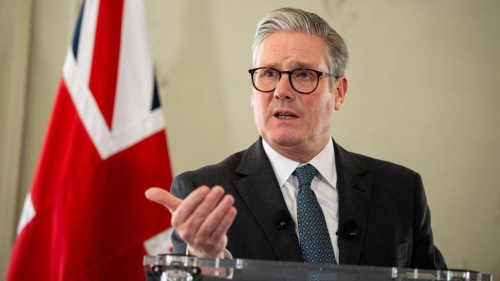 Keir Starmer, UK prime minister, wears a suit and stands next to a Union Flag