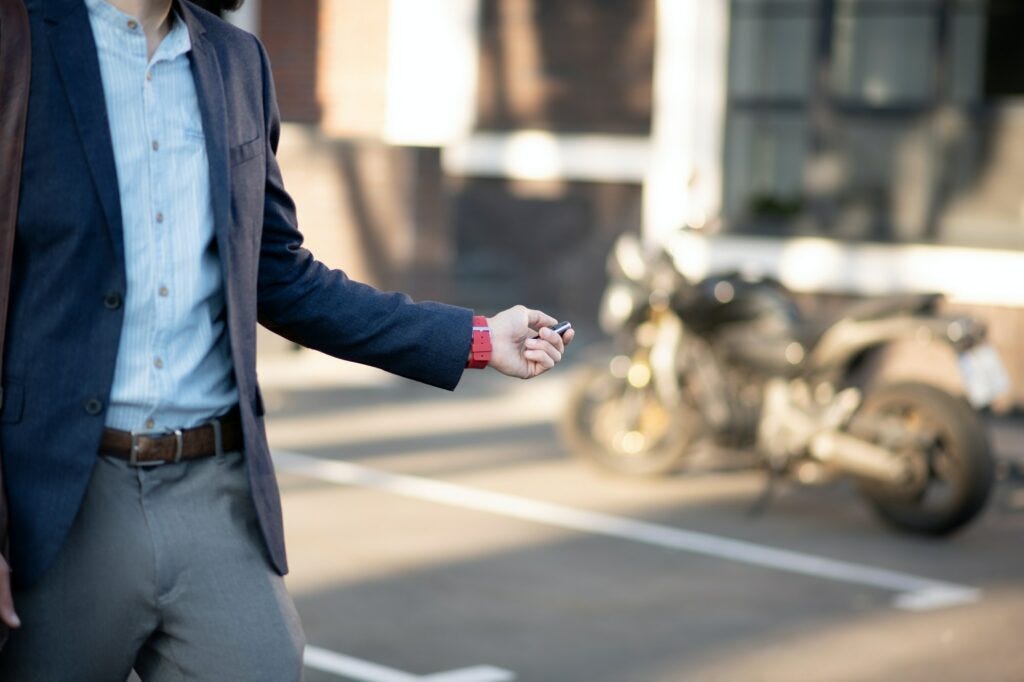 Businessman wearing dark jacket unlocking his motorcycle Businessman wearing dark jacket unlocking his motorcycle