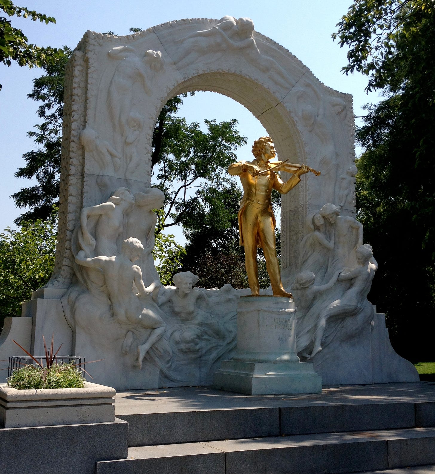 The golden statue of Johann Strauss II in Vienna's Stadtpark, in the midday sun.