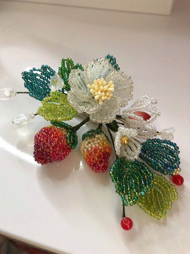 This may contain: a close up of a flower on a white surface with berries and leaves attached to it