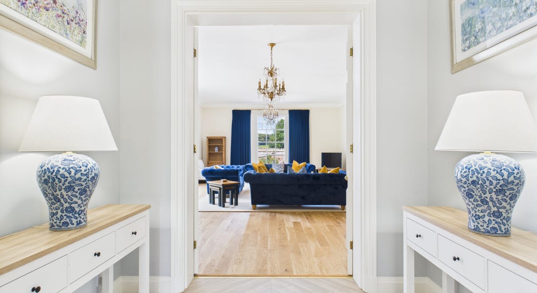 A large white hallway with two lamps eitherside, looking onto a living room