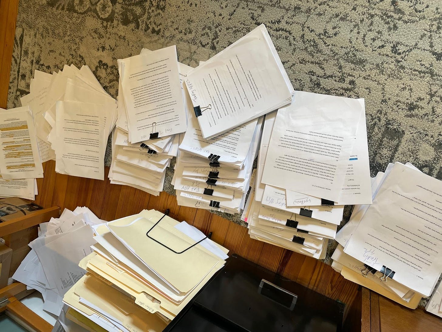 Image of stacks of paper on the floor with paper clips. It's a big giant mess of paper
