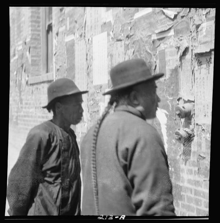 An archive photo depicting two men reading a notice in Chinatown An archive photo depicting two men reading a notice in Chinatown