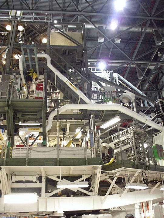 A blurry picture of a vaguely-shuttle-shaped shell of scaffolding and machinery in the OPF, behind which I swear there is an actual space shuttle.