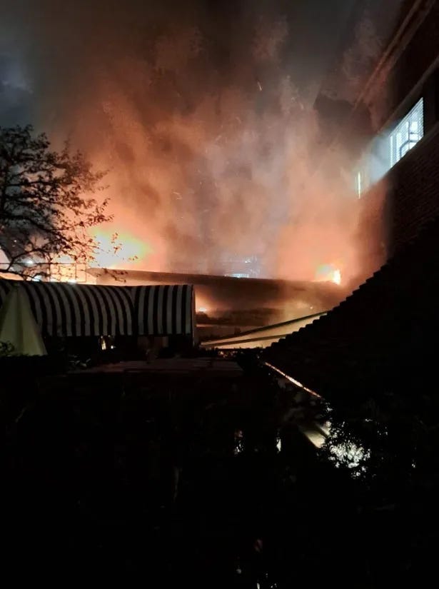 Fire and smoke spreading across several buildings at night.