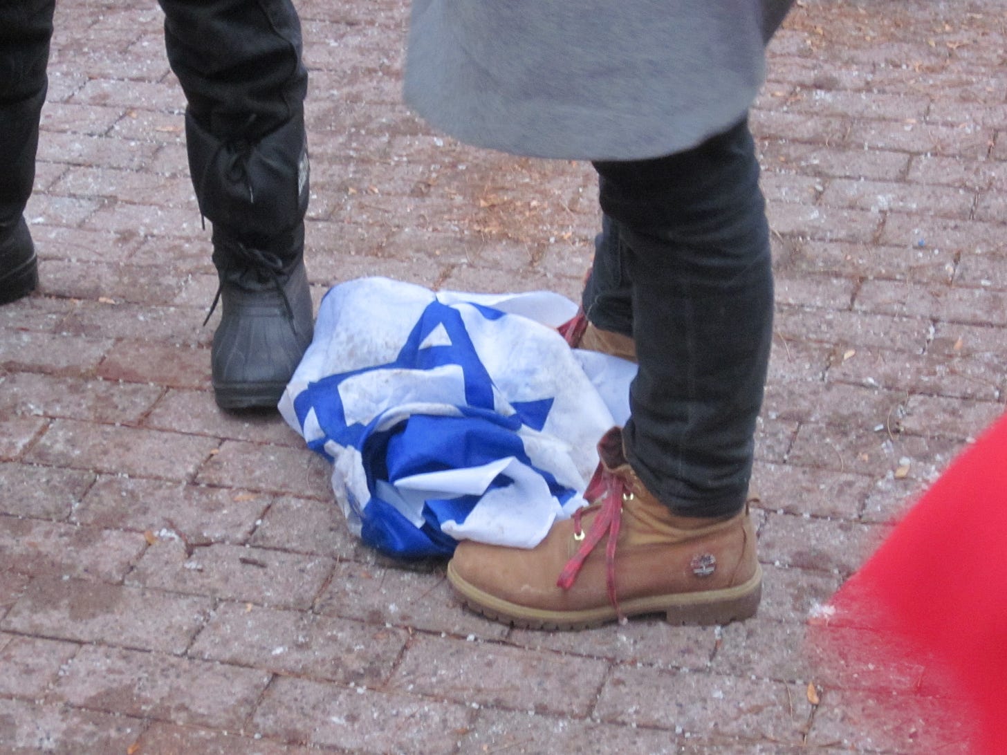 An Israeli flag brought by a protestor, thrown on the ground and stomped on. An Israeli flag brought by a protestor, thrown on the ground and stomped on.