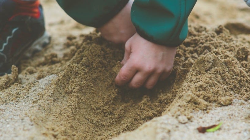 person in blue long sleeve shirt and blue denim jeans standing on brown sand during daytime person in blue long sleeve shirt and blue denim jeans standing on brown sand during daytime