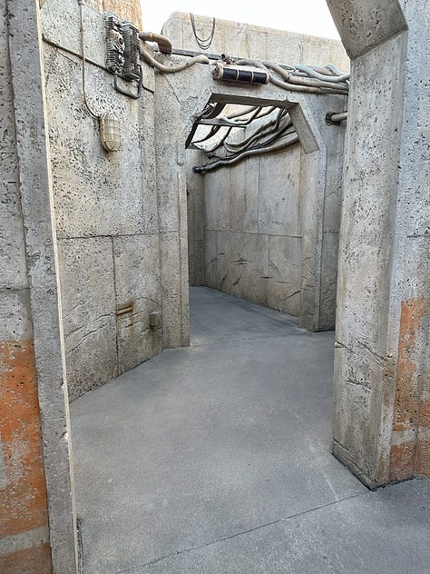 A series of images showing first the narrow passage way leading from the transport to Black Spire Outpost, then the massive TIE fighter and a few buildings in the outpost