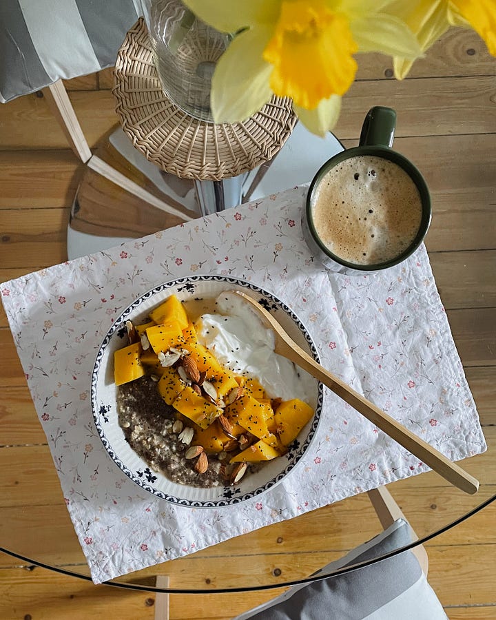 Image 1: A breakfast table with a chia, almond, and mango bowl, coffee, and daffodils in a vase. / Image 2: A close-up of the breakfast bowl, showing the mango’s vibrant colour and the toppings.