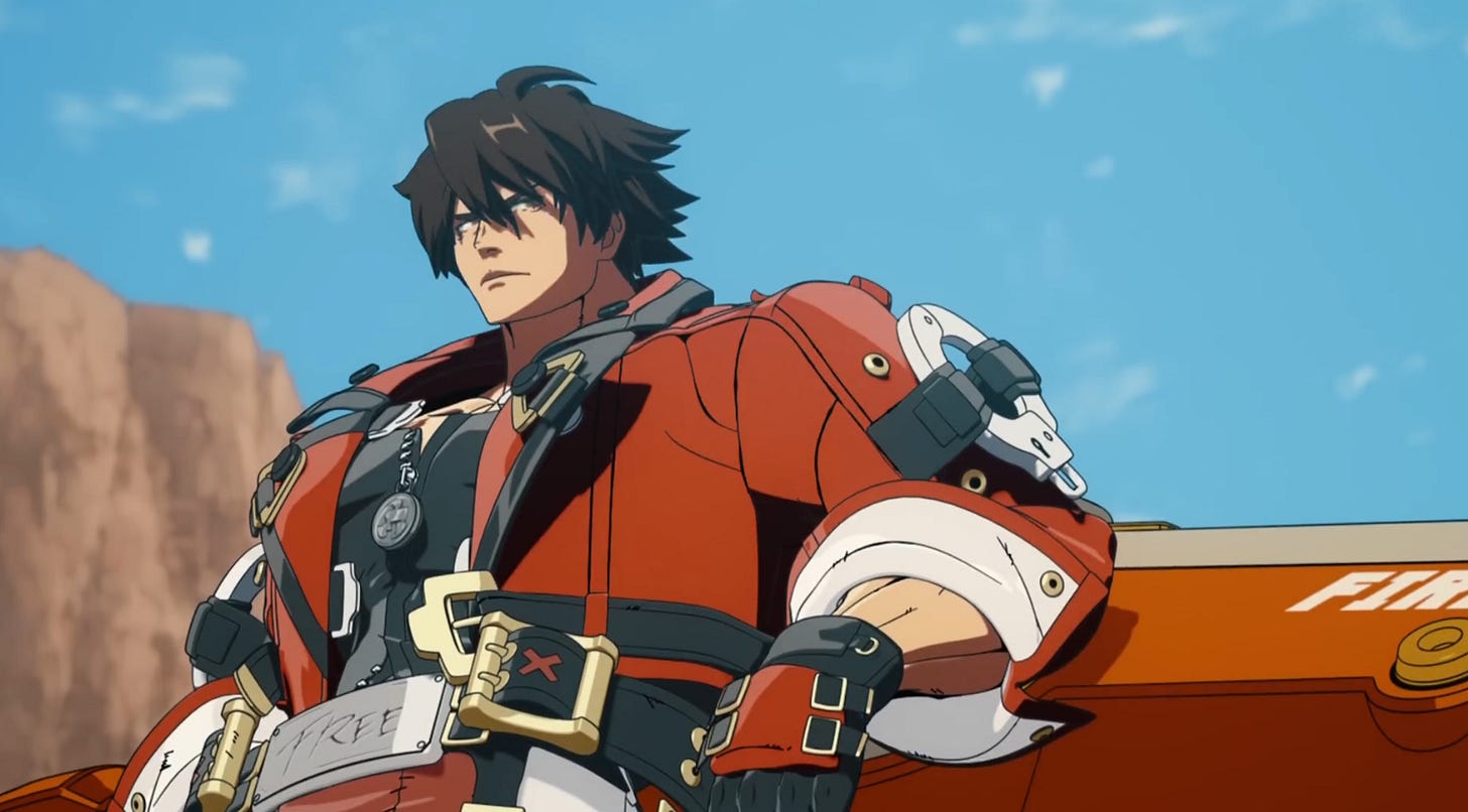 Sol leaning against the Fire-Wheel motorcycle in a closeup shot. His expression is stoic. There is a brown cliff face and a light blue sky behind him.