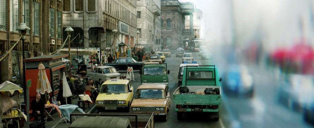 A scene from the BBC's adaptation of The City & The City, showing two sides of a busy street, with one side blurred out to show how an inhabitant of one city cannot see the other.