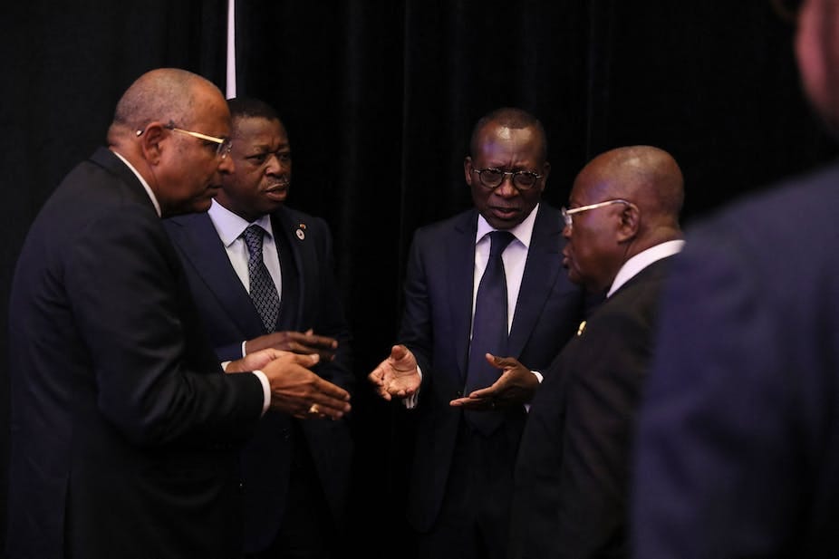 Four men stand together talking Four men stand together talking