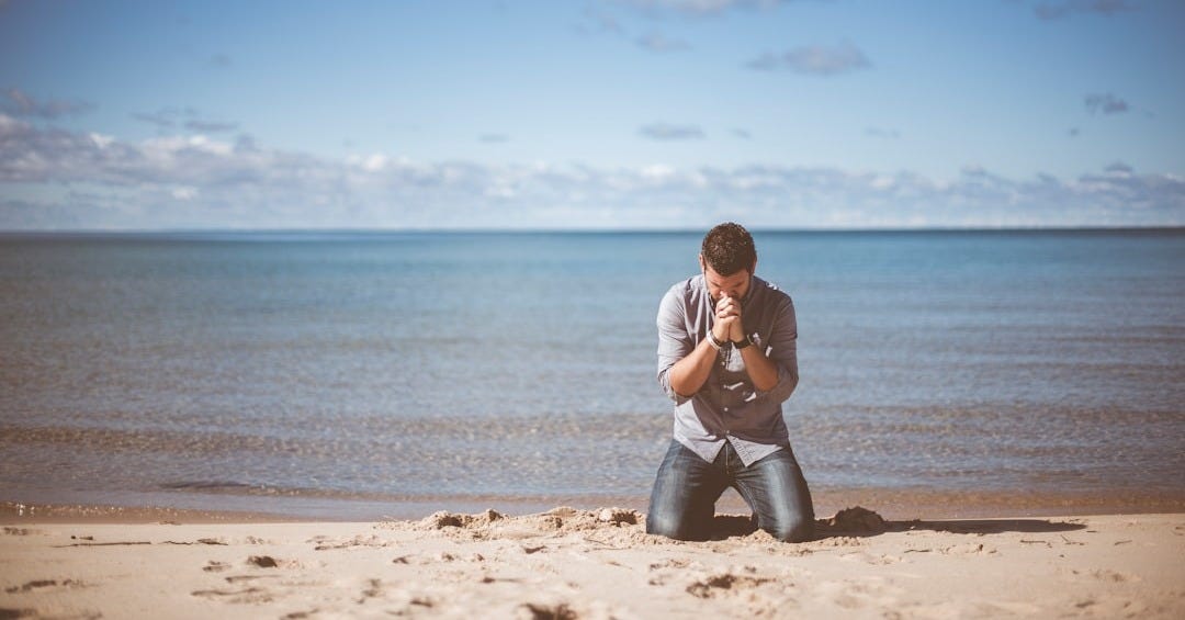 man kneeling down near shore