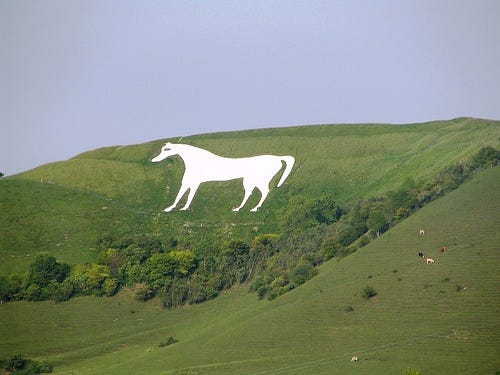 This may contain: a large white horse statue on top of a green hill
