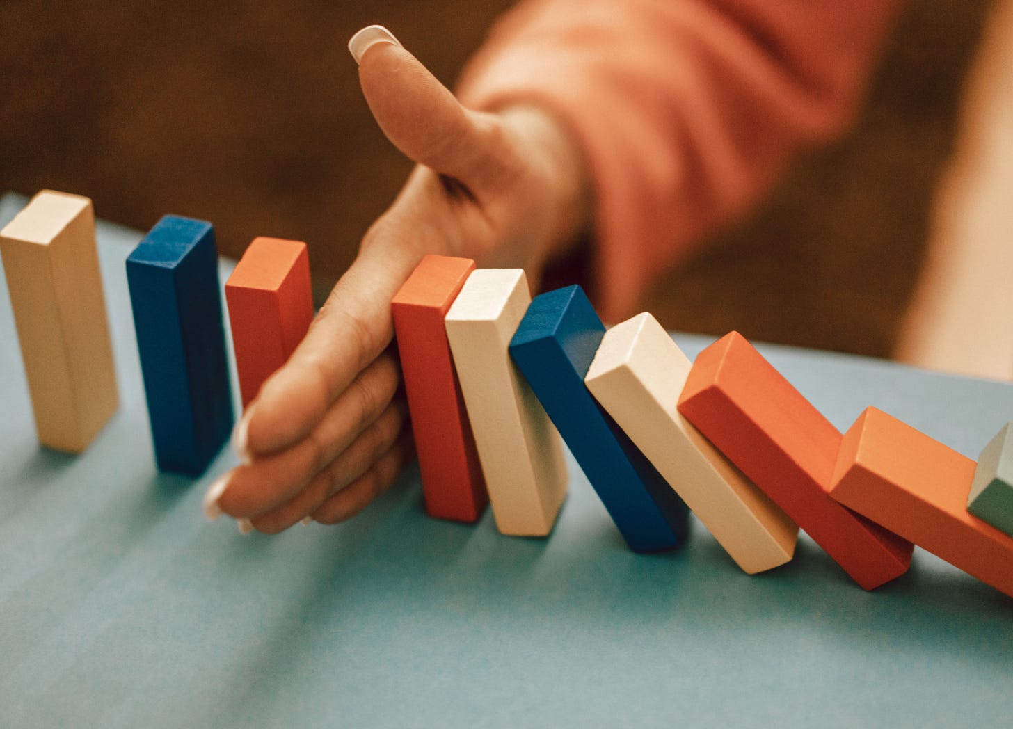 Hand stopping falling dominoes mid-collapse.