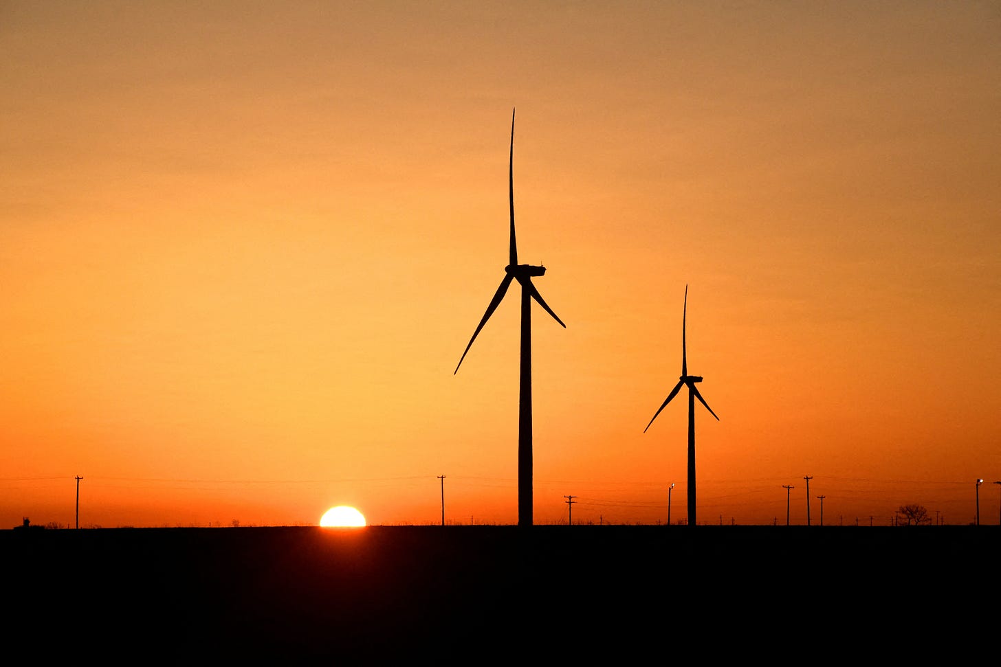Wind turbines operate at sunrise in the Permian Basin oil and natural gas production area in Big Spring