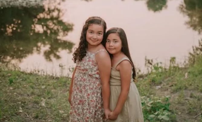 Two girls holding hands and standing next to each other

Description automatically generated