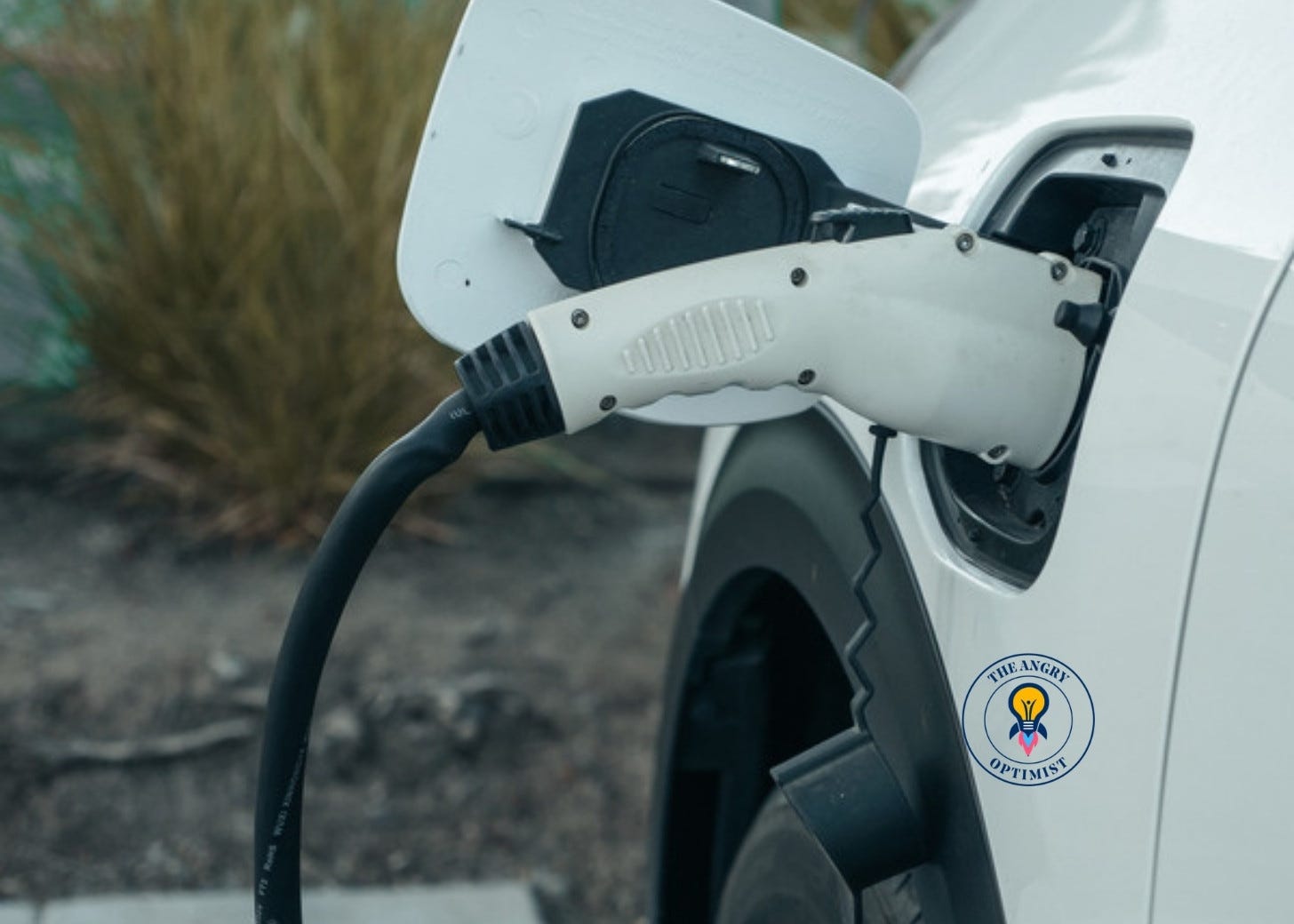A charging cable plugged into the charging port of a white electric car A charging cable plugged into the charging port of a white electric car