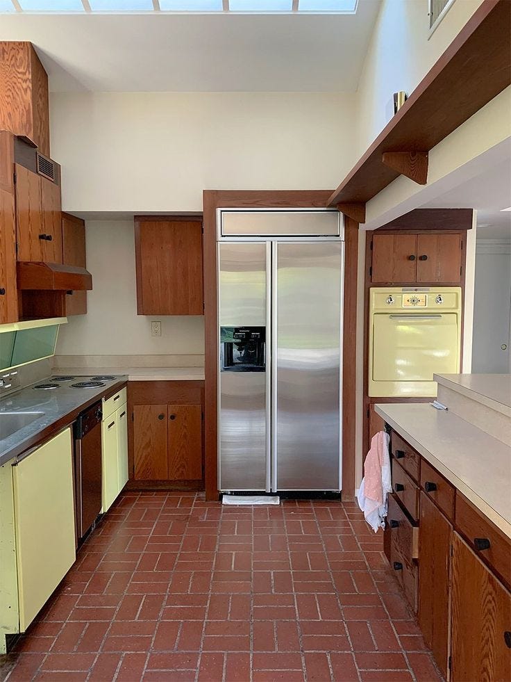 This may contain: a kitchen with tile flooring and wooden cabinets, including a stainless steel refrigerator freezer