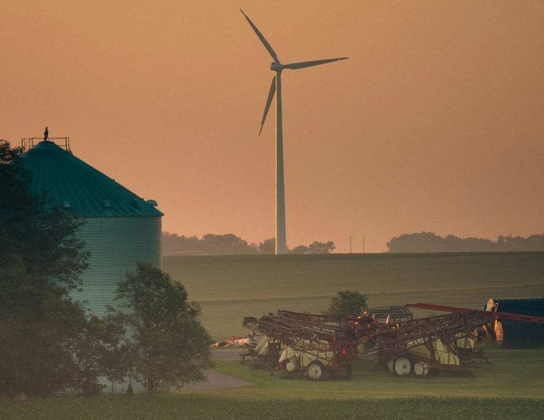 a farm field with a wind turbine in the background a farm field with a wind turbine in the background