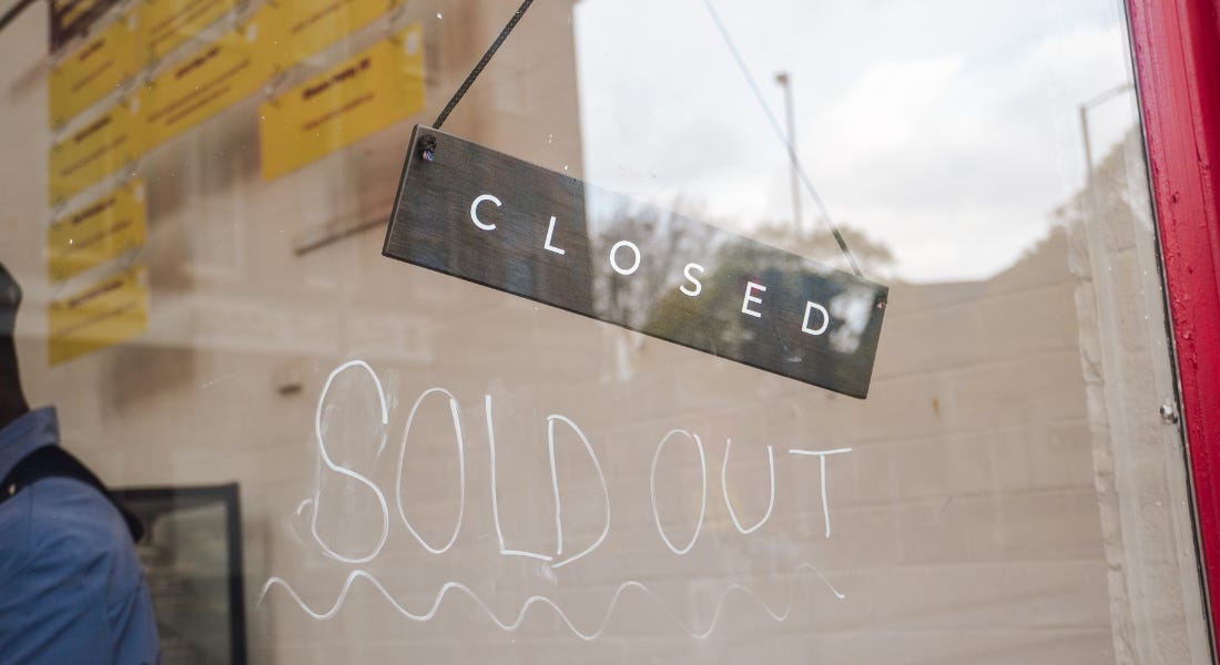 A sign that says 'closed' with white writing on the window that says 'sold out'
