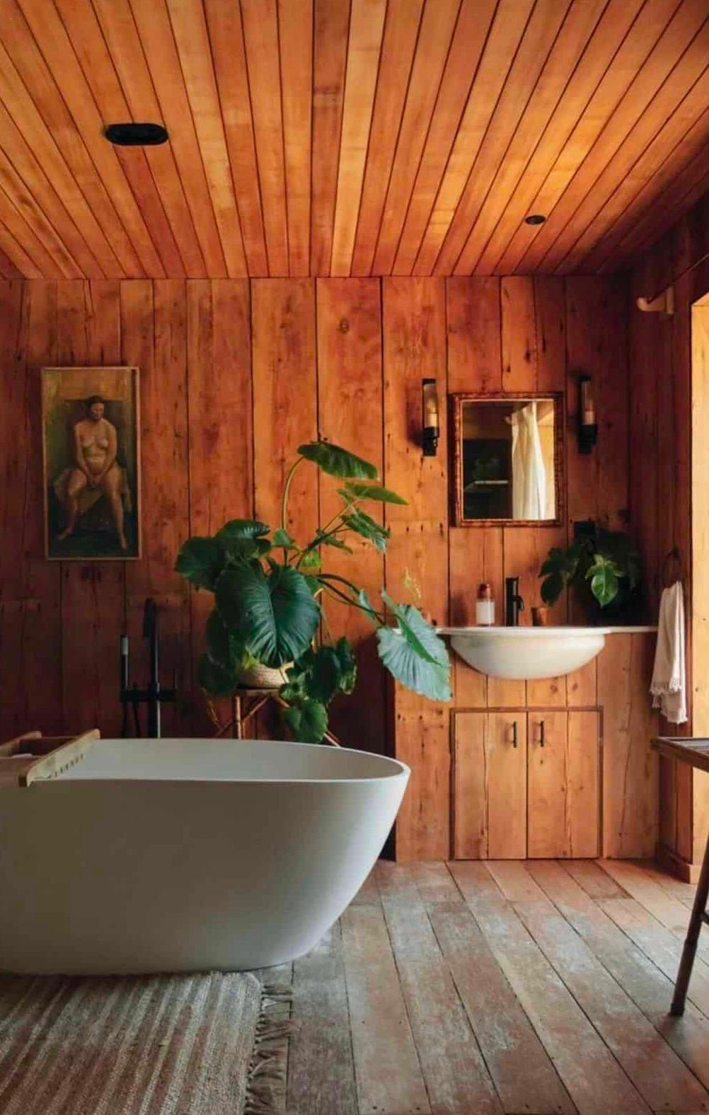 a redwood bathroom with a free-standing tub, a giant indoor plant, and vintage art. a redwood bathroom with a free-standing tub, a giant indoor plant, and vintage art.