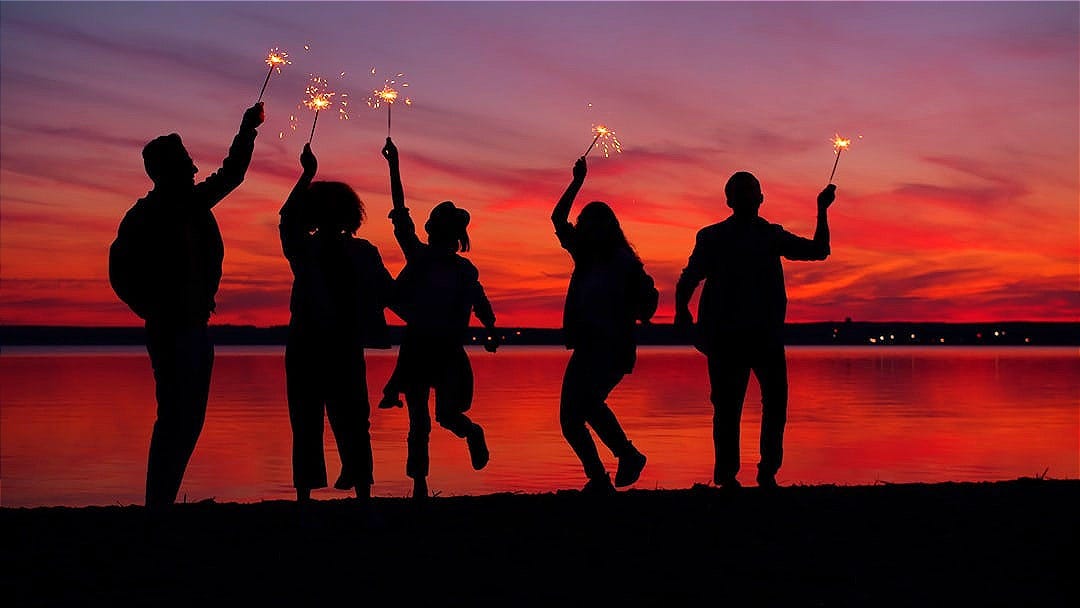 Silhouettes of people celebrating with sparklers at sunset. Silhouettes of people celebrating with sparklers at sunset.