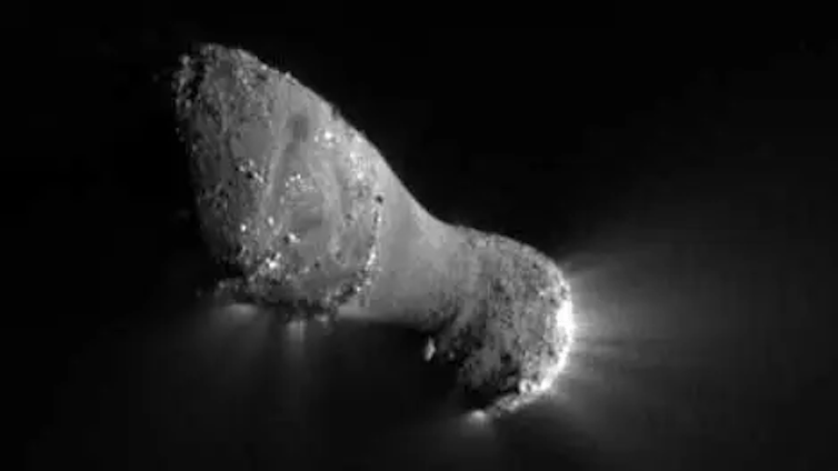 A photo of an oval-shaped comet, with light illuminating it from the back side, which has a sparse trail of dust particles. A photo of an oval-shaped comet, with light illuminating it from the back side, which has a sparse trail of dust particles.
