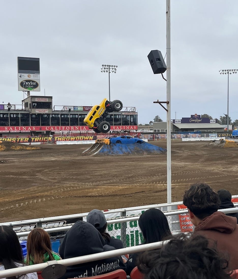 A yellow monster truck gets some air as it accelerates up a ramp. 