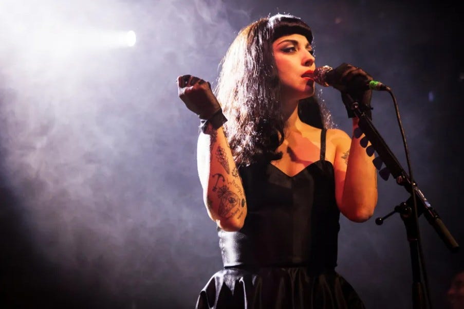 Mon Laferte peforms onstage in a smoky venue. Mon Laferte peforms onstage in a smoky venue.