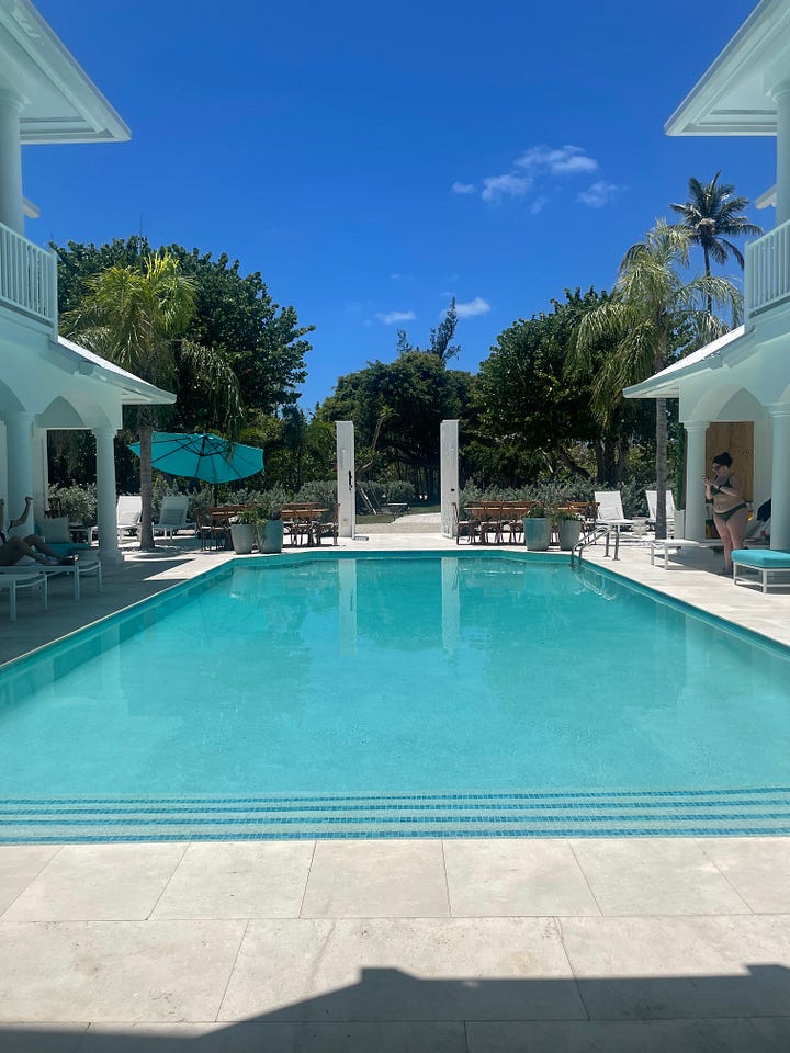 First picture of an aqua pool surrounded by beige tile with palm trees in the background. Second picture of a soft waves coming onto a white sand beach with some reeds and shrubs.
