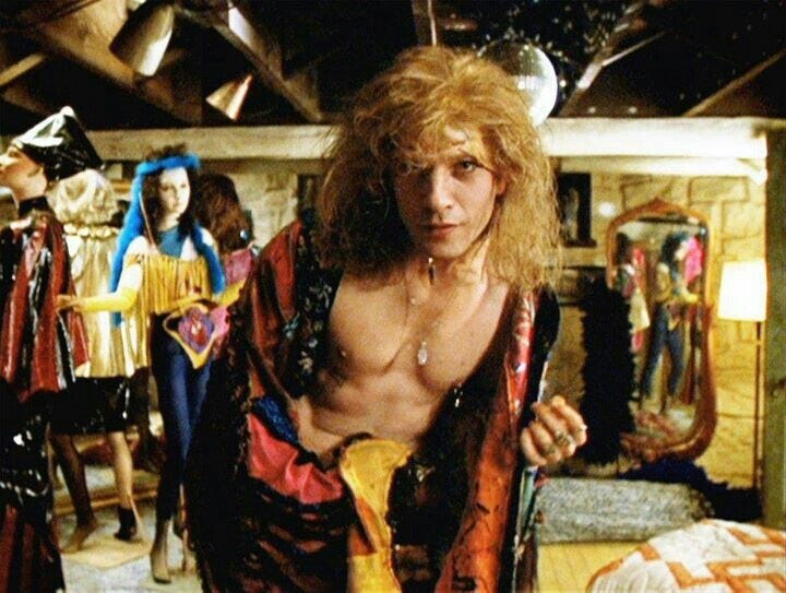 This may contain: a man with long hair and no shirt is posing for the camera, wearing a tie